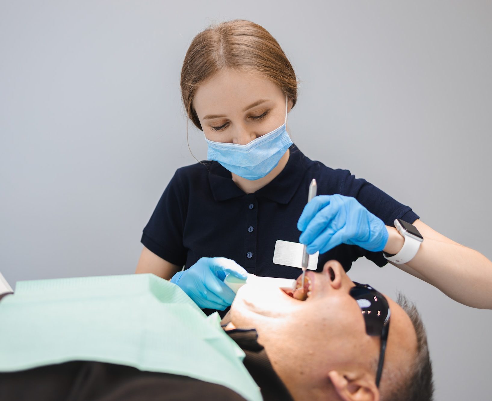 Female dentist filling man's teeth