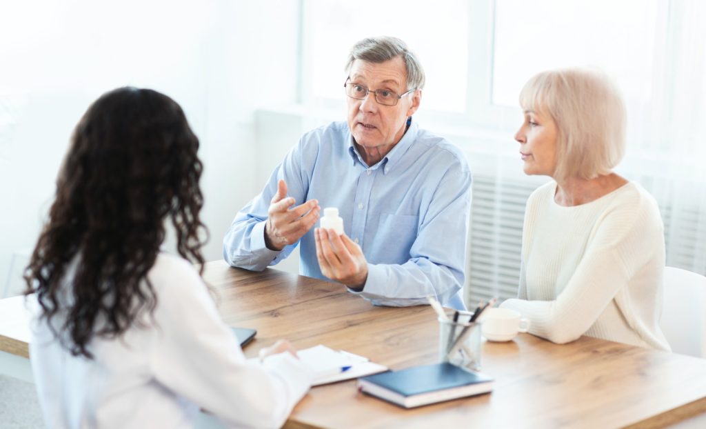 Mature couple asking doctor how to use pill