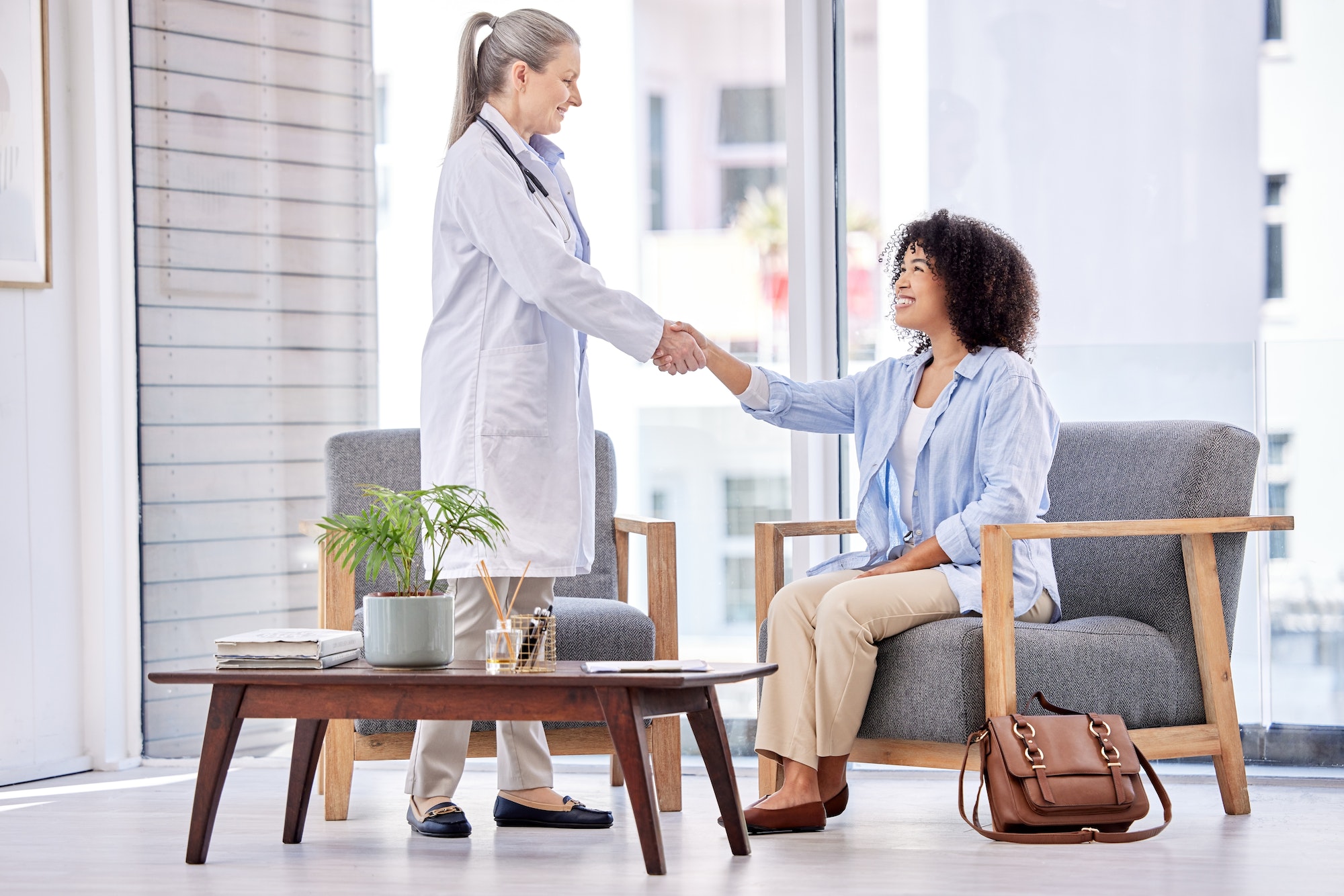 Shot of a mature female doctor shaking hands with a patient in an office