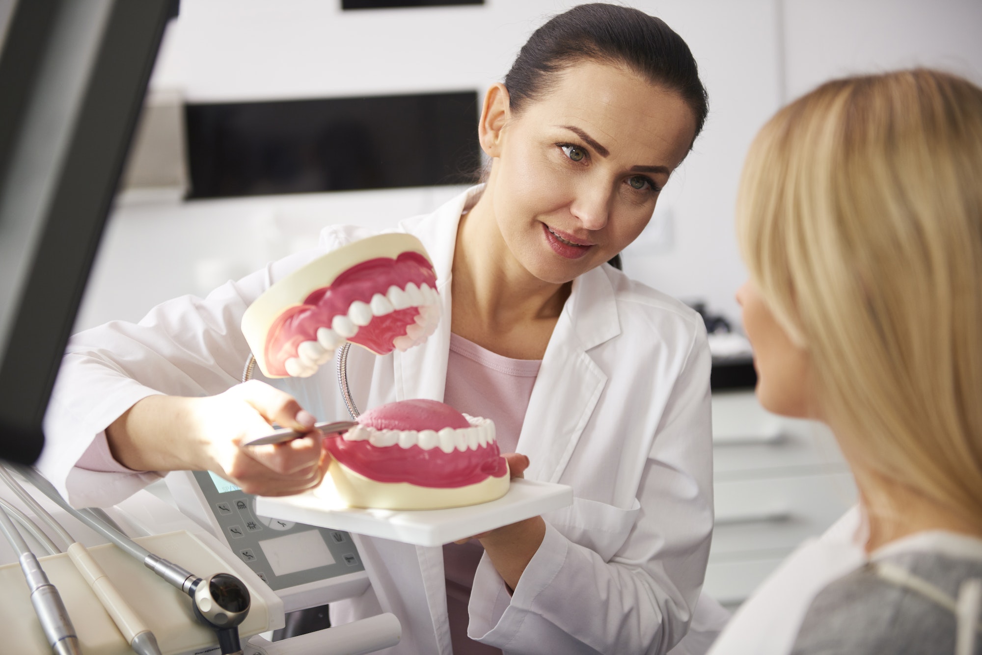 Smiling dentist showing patient the artificial dentures