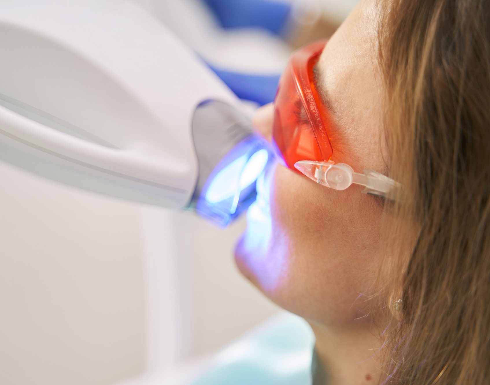Woman receiving laser whitening treatment in dental clinic