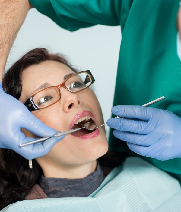 woman having dental check up in dental office. Dentist examining a patient's teeth with dental